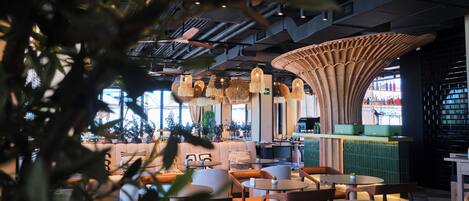 Een modern interieur met een centraal zithoek, tafels en een opvallende, gebogen plafondconstructie.