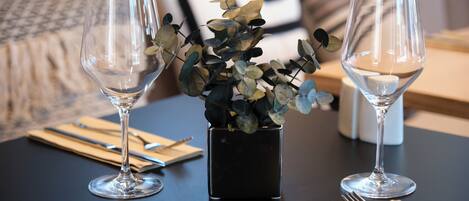A dining table with two wine glasses and a small potted plant.