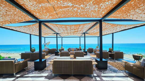 A covered outdoor seating area with wicker furniture and a view of the beach. - ESTIMAR Marina Farnals (La Pobla de Farnals)