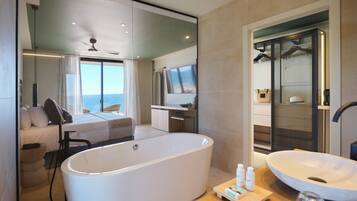 Un baño moderno con una bañera independiente, un tocador con un lavamanos grande y una zona de estar con vistas al mar.