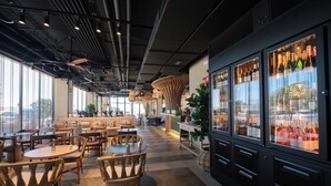 A modern restaurant with a checkered floor, wooden tables, and chairs. There are large windows on one side and a wine refrigerator on the other. - ESTIMAR Marina Farnals (La Pobla de Farnals)