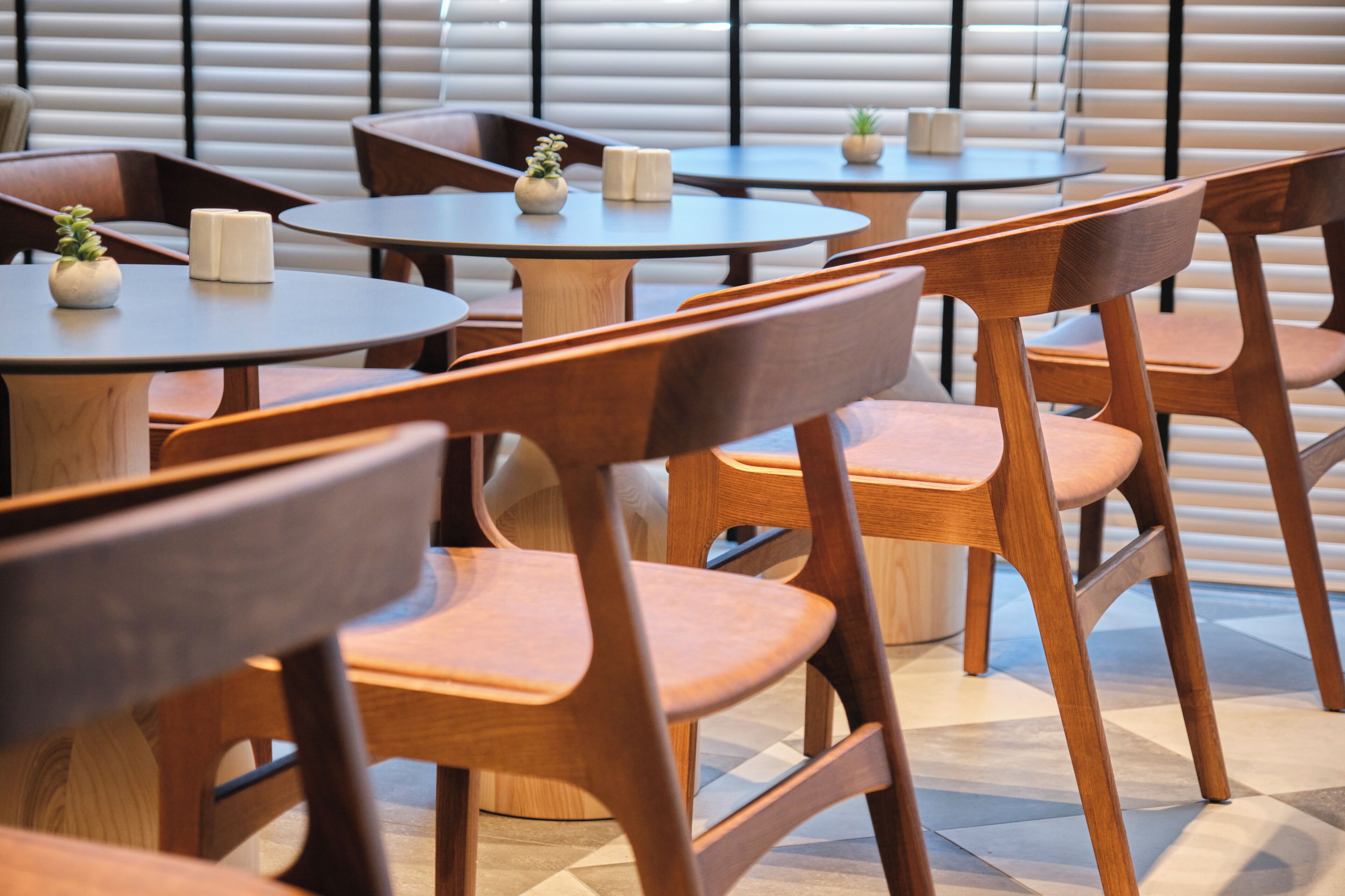 Een restaurantinterieur met ronde tafels en houten stoelen.