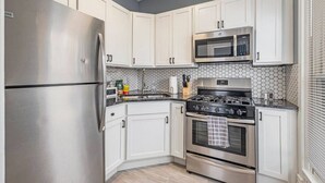 Una cocina moderna con electrodomésticos de acero inoxidable, armarios blancos y un salpicadero de azulejos hexagonales.