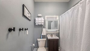 Un baño pequeño con inodoro, lavamanos y barra para toallas.