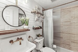 A bathroom with a white sink, a round mirror, a toilet, and a shower area with a curtain.