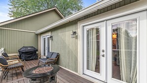 An outdoor patio with a stone fire pit, wicker chairs, and a grill. - Edelweiss Chic Retreat /Grand Park/Ruoff/ Extended Stays Accepted
 (Noblesville)