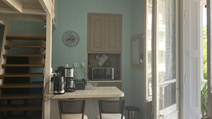 A kitchen with a built-in microwave, a coffee maker, and a clock on the wall. There are two bar stools and a trash can. - Studio  in a 19th century villa with parking (Villers-sur-Mer)