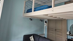 A room with a bunk bed, a couch, a door, and a mirror on the wall. - Studio  in a 19th century villa with parking (Villers-sur-Mer)