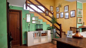 A room with a wooden staircase, a bookshelf, and a dining table.
