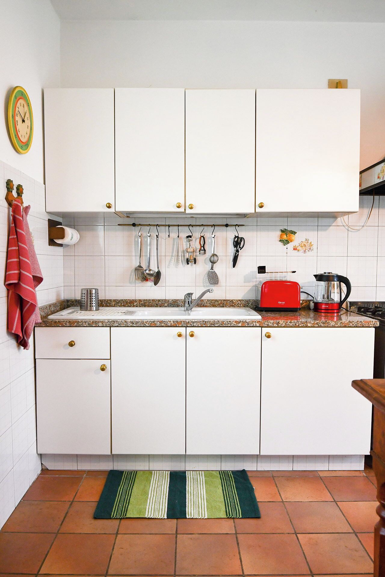 A kitchen with white cabinets, a red toaster, and a coffee maker.