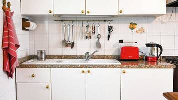 A kitchen with white cabinets, a red toaster, and a coffee maker.