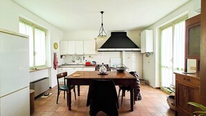 A kitchen with white cabinets, a wooden table, and a black hanging light fixture.