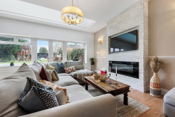 A living room with a fireplace, large windows, and a view of the outdoors.