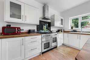 A modern kitchen with white cabinets, a red microwave, a gas stove, and a window with a view of greenery.