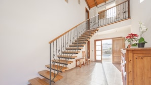 A spacious interior with a wooden staircase, a dining area, and a view through a glass door.