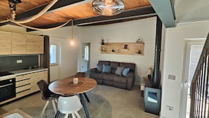 Une cuisine moderne avec des meubles de rangement en bois, une table à manger avec des chaises, un canapé et un luminaire suspendu.