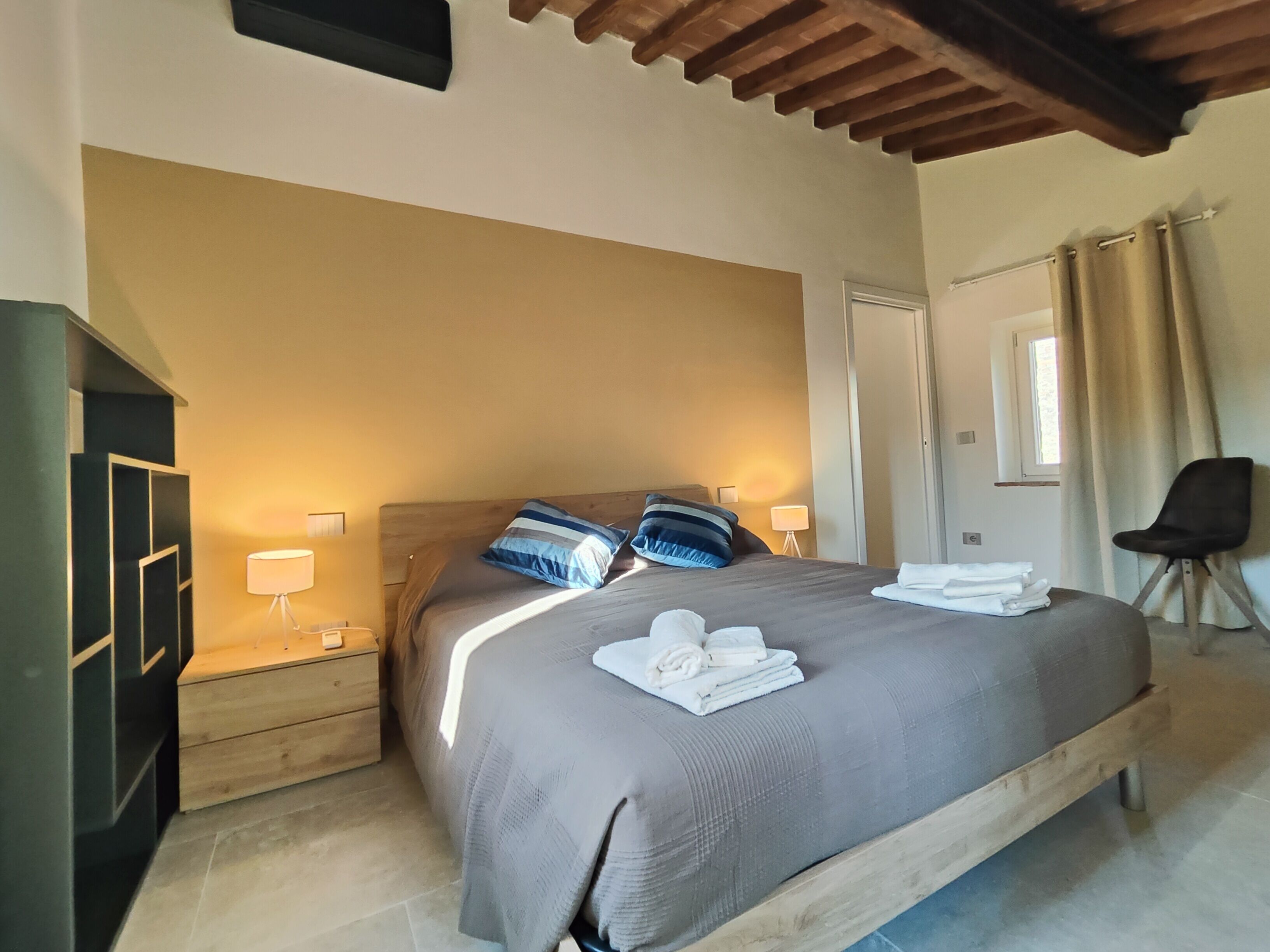 A bedroom with a bed, nightstands, a wardrobe, and a chair.