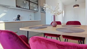 Una cocina moderna con una mesa de madera, sillas rojas y un jarrón con flores blancas.