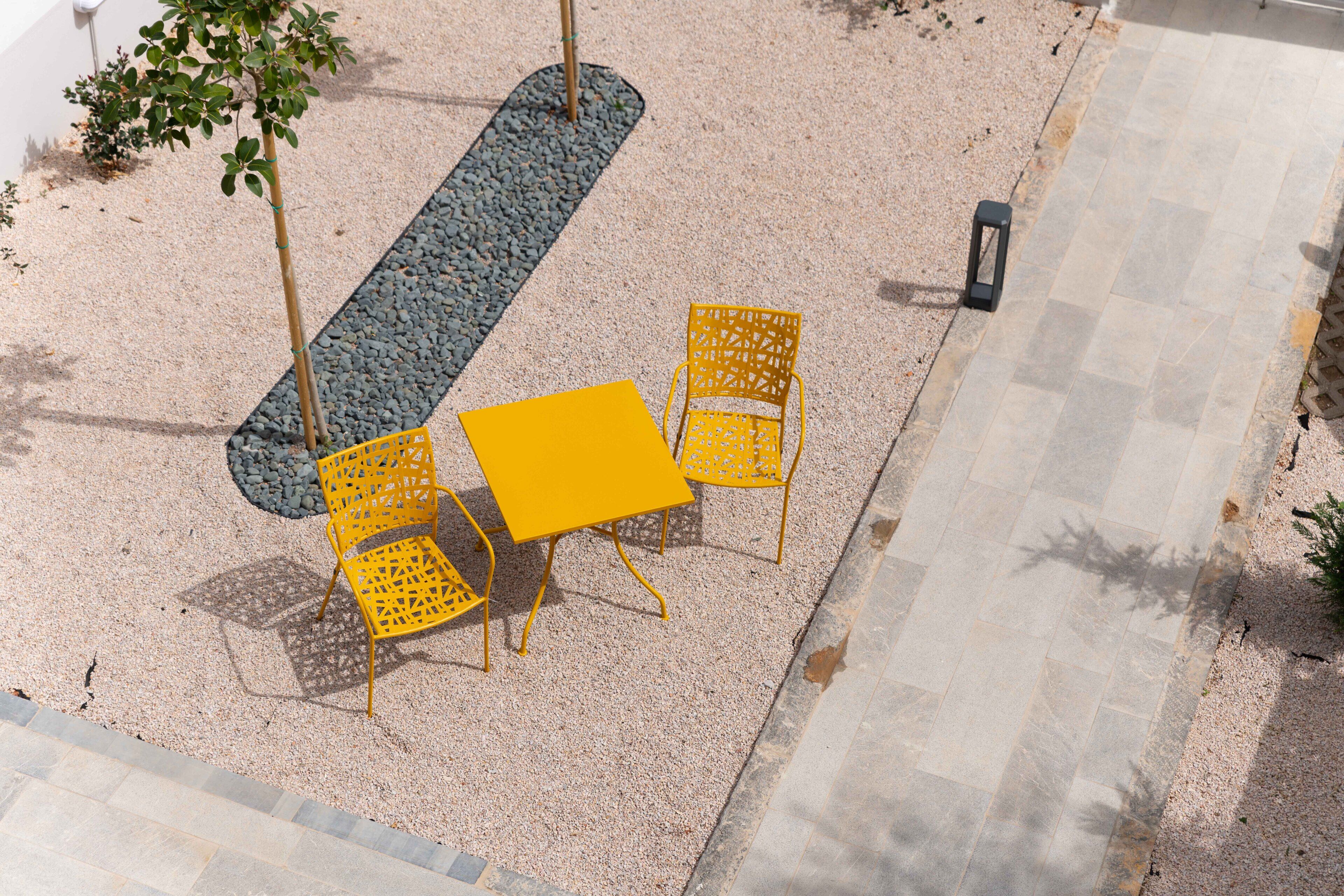 An outdoor seating area with a table and chairs, surrounded by gravel and a pathway.