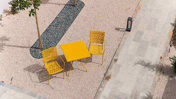 An outdoor seating area with a table and chairs, surrounded by gravel and a pathway.