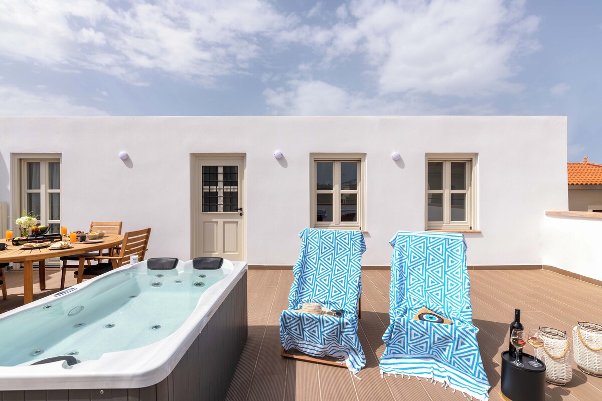 Una terraza en la azotea con hidromasaje, dos sillones, una mesa de comedor con sillas y un área de bar con botellas y vasos.