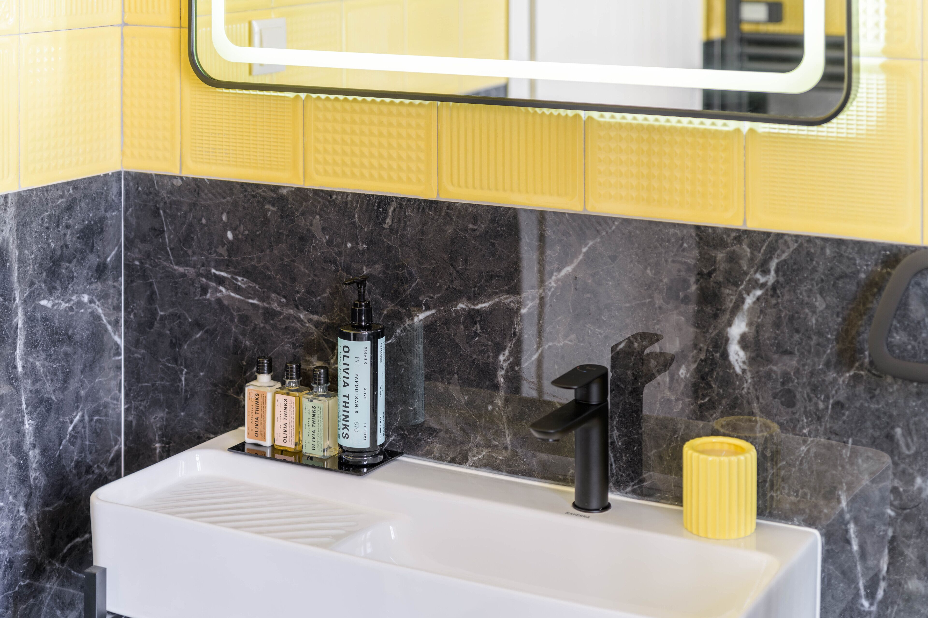 A bathroom with a white sink, black faucet, and yellow-tiled walls.