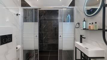 A modern bathroom with a glass-enclosed shower, a white sink, and a mirror with a neon light.