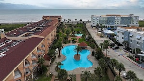 A hotel with a swimming pool, a beach view, and multiple buildings. - Beachfront resort style in Galveston - 3 Pools - Pet Friendly! (Galveston)