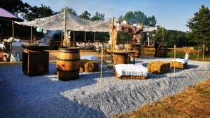 Ein Open-Air-Event mit Fässern, Heuballen und einem Zelt.