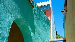 A staircase with colorful steps leading up to a building with a teal facade and a white roof. - Villaggio Colostrai (Muravera)