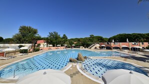 A large outdoor swimming pool with multiple lanes, lounge chairs, and umbrellas. - Villaggio Colostrai (Muravera)
