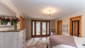 Ein Schlafzimmer mit einem großen Bett, einer Holzkommode, einem Spiegel und einem Rindelleder-Teppich.