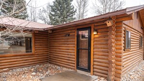 Eine Blockhütte mit Metalldach, einer Haustür und einer kleinen Veranda.