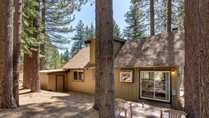 A cabin with a deck, surrounded by tall trees.
