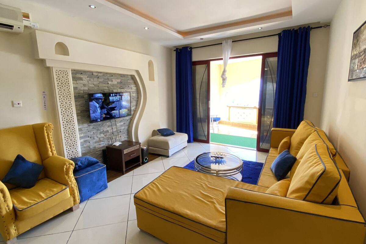 A living room with yellow sofas, a TV, and a fireplace.