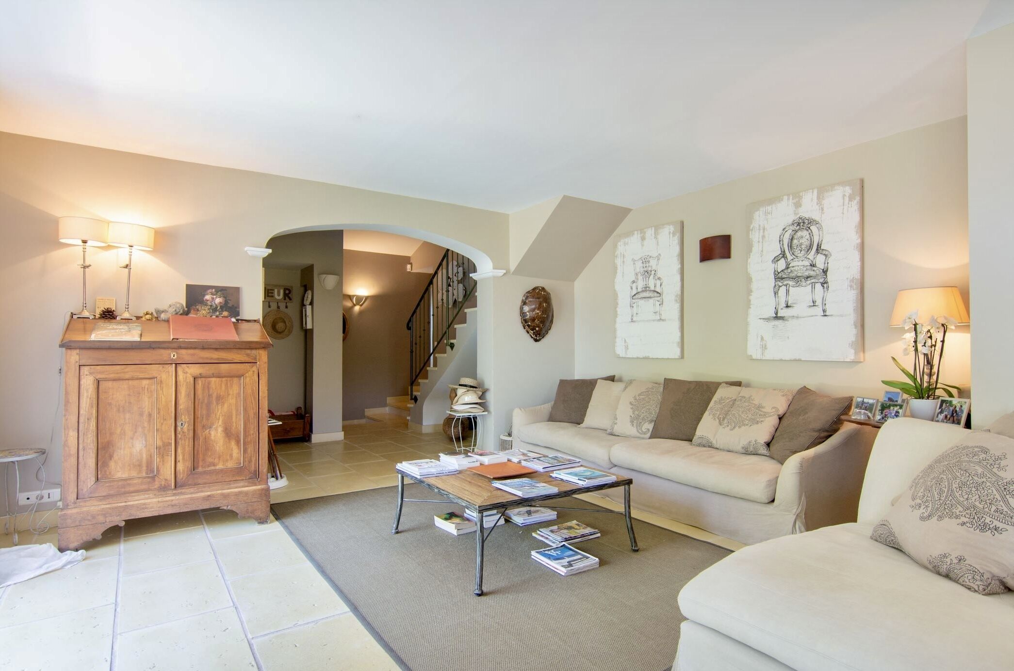 A living room with a sofa, coffee table, and wooden cabinet. There is a staircase leading to another room.