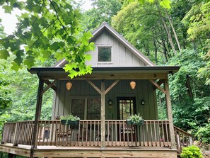 A wooden cabin with a porch, surrounded by trees. - Whimsical Creekside Cabin (Vesuvius)