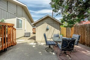 A patio with a table and chairs, a wooden fence, and a shed. - Bruneau Bungalow Side A (Kennewick)