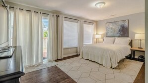 Una camera da letto con un letto, una scrivania, una sedia, una lampada e un quadro appeso al muro.