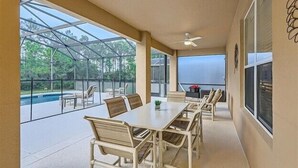 Un porche techado con una mesa y sillas, con vista a una piscina.