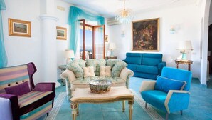 A spacious living room with a large window, a chandelier, and a painting on the wall. - Casa Duca, apartment with sea views in Sorrento (Meta di Sorrento)