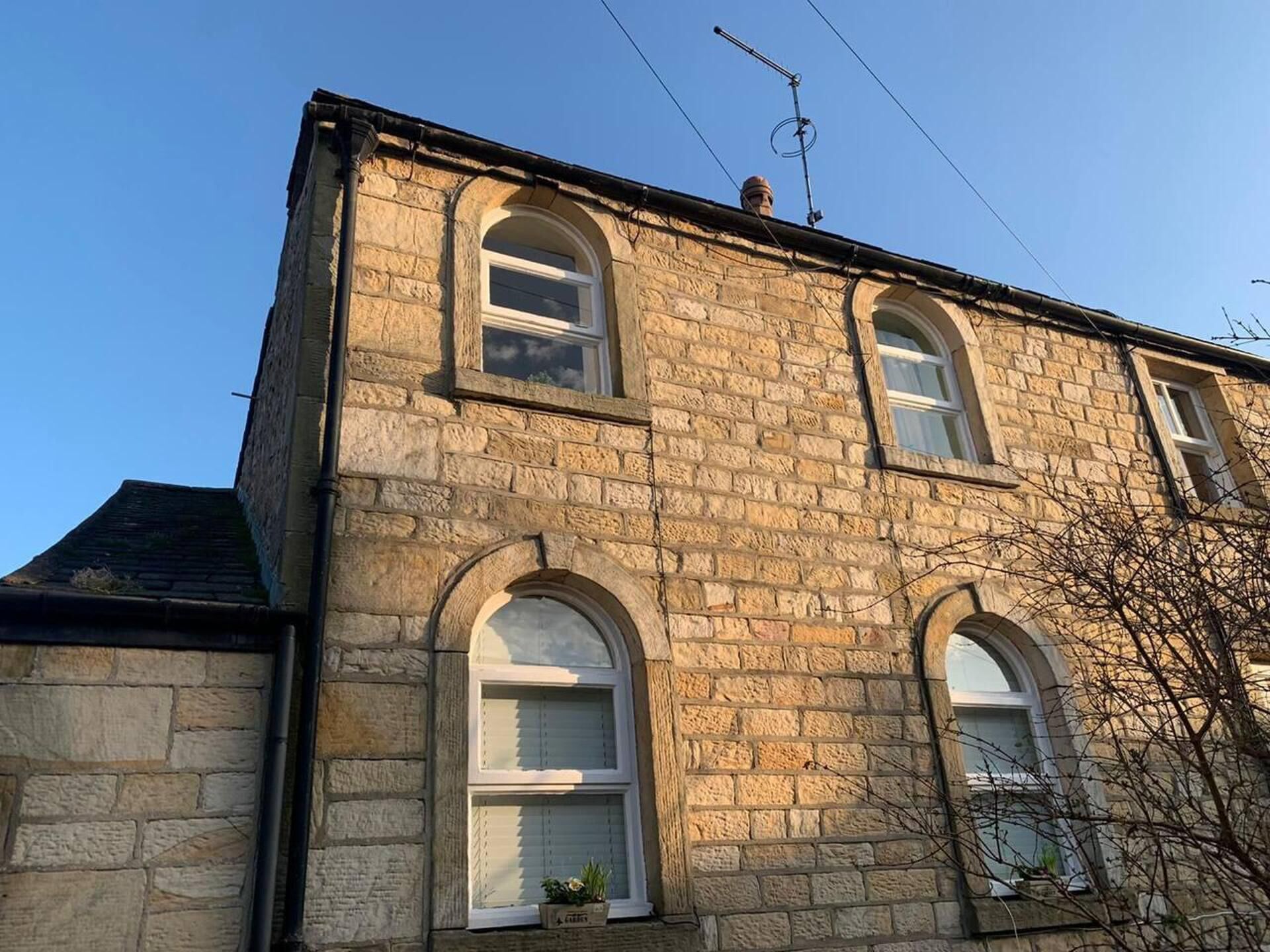 A stone building with three arched windows and a chimney.