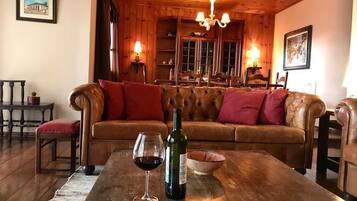 A cozy living room with a leather sofa, a wooden coffee table, a wine glass, and a bottle of wine.