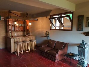 A cozy room with a wooden bar area, a leather sofa, and a small table with a lantern. - Country Home (Campos do Jordão)