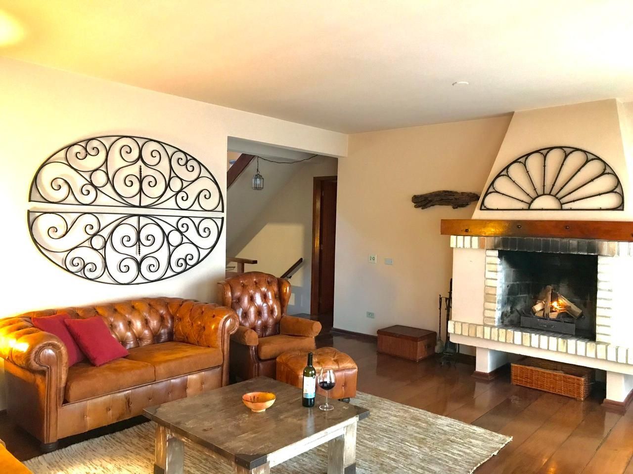 A living room with a fireplace, a leather sofa, a wooden coffee table, and decorative wall art.