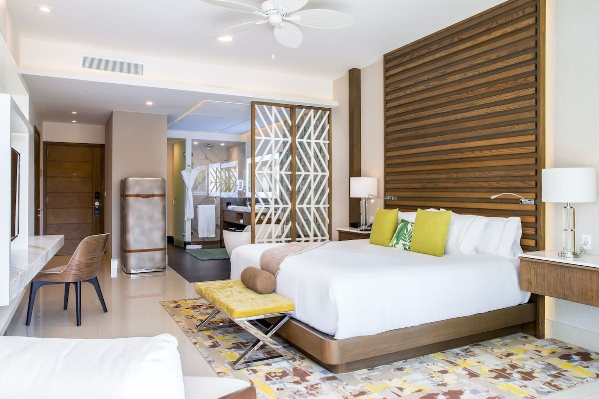 A modern hotel room with a large bed, a desk, and a seating area.