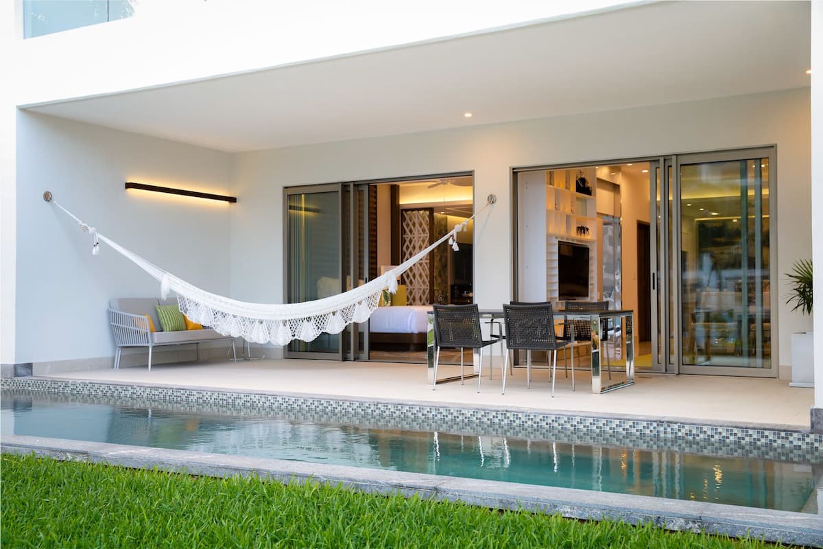 A modern outdoor area with a pool, a hammock, and a seating area with chairs and a table.