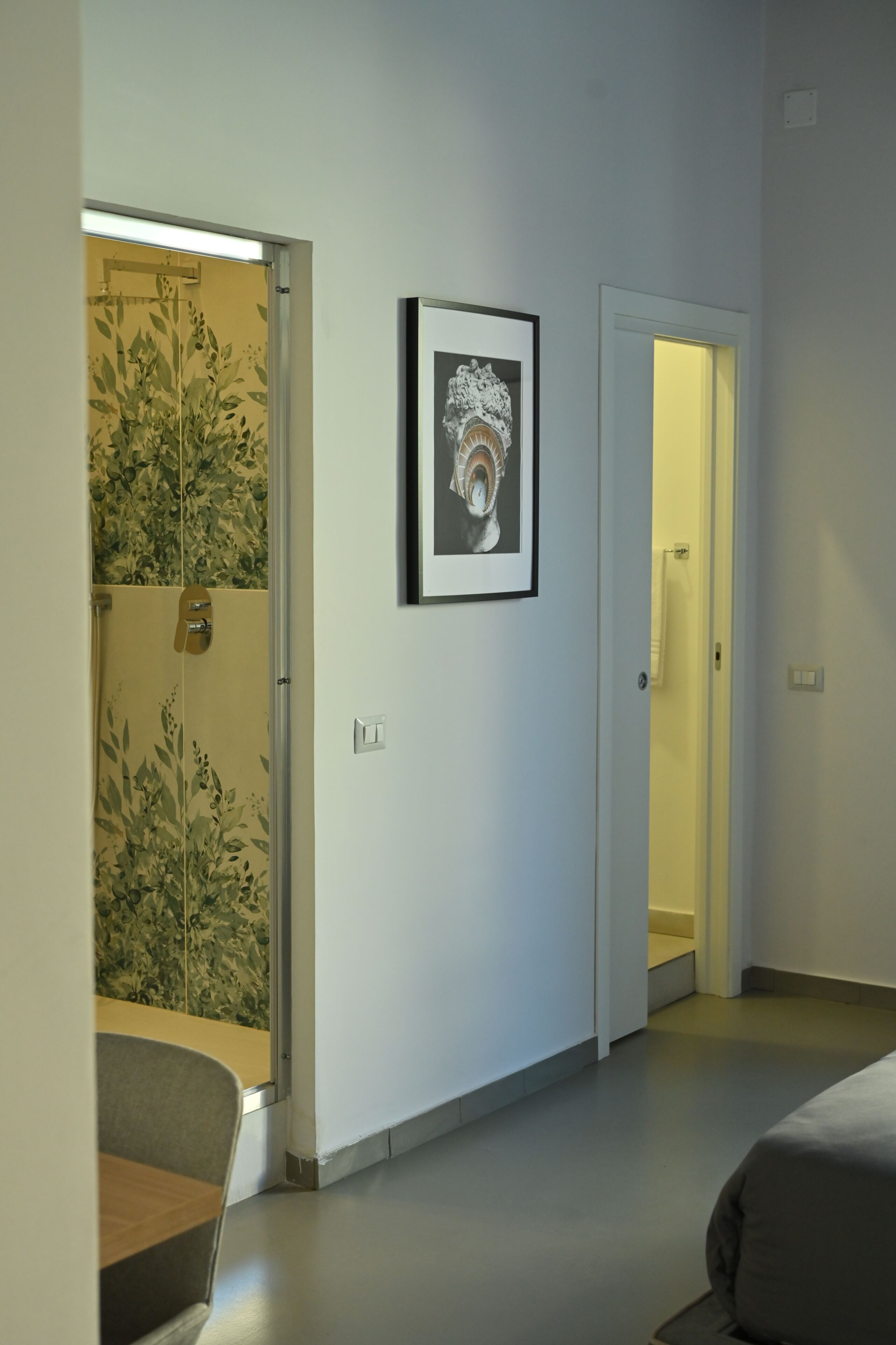 A bedroom with a bed, a framed picture on the wall, and a bathroom door.
