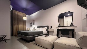 A hotel room with a bed, a desk with a mirror, a chair, and a small table. - Ghe Kale' Resort (San Paolo Bel Sito)
