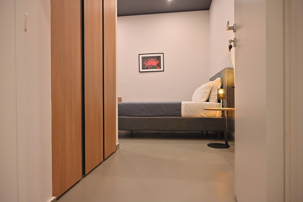 Une chambre à coucher avec un lit, une table de chevet, une lampe et un tableau encadré au mur.